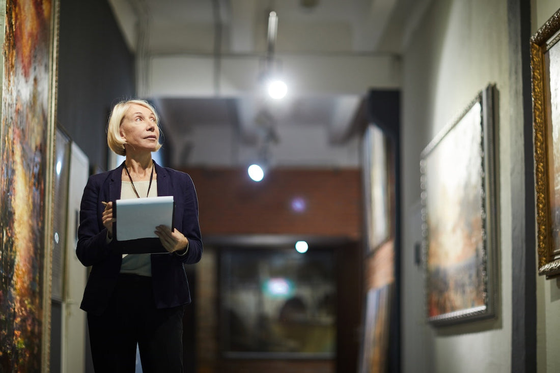 A female museum curator holding a clipboard while looking at art in an art gallery
