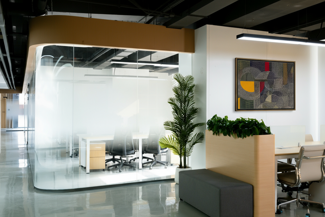 A meeting room with frosted glass next to office workstations decorated with a large wall art.