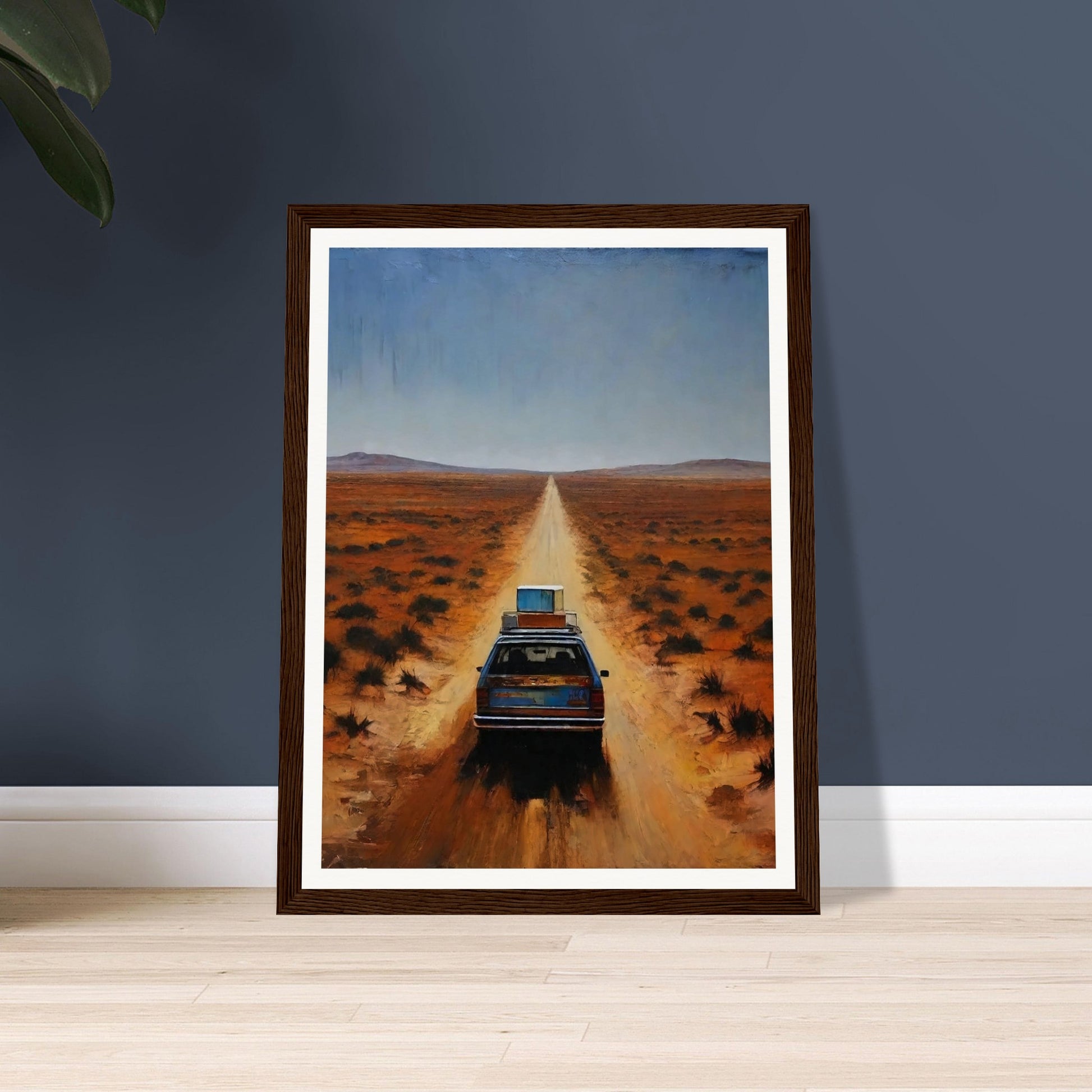 A car driving down a long, desolate road in a vast desert landscape under a clear blue sky.
