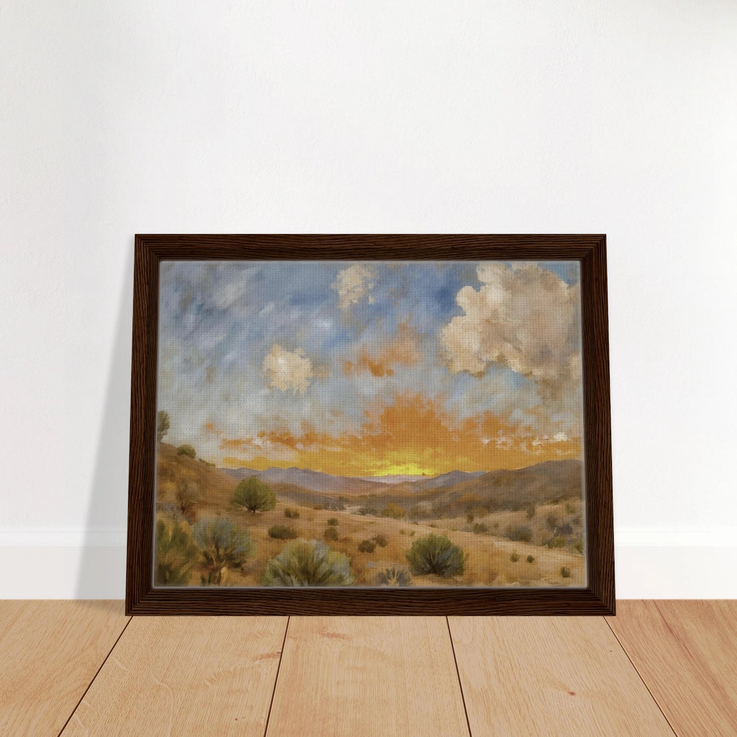A glowing orange sunset spreads over a tranquil desert valley with scrubby bushes, rolling hills, and dramatic cloud cover.
