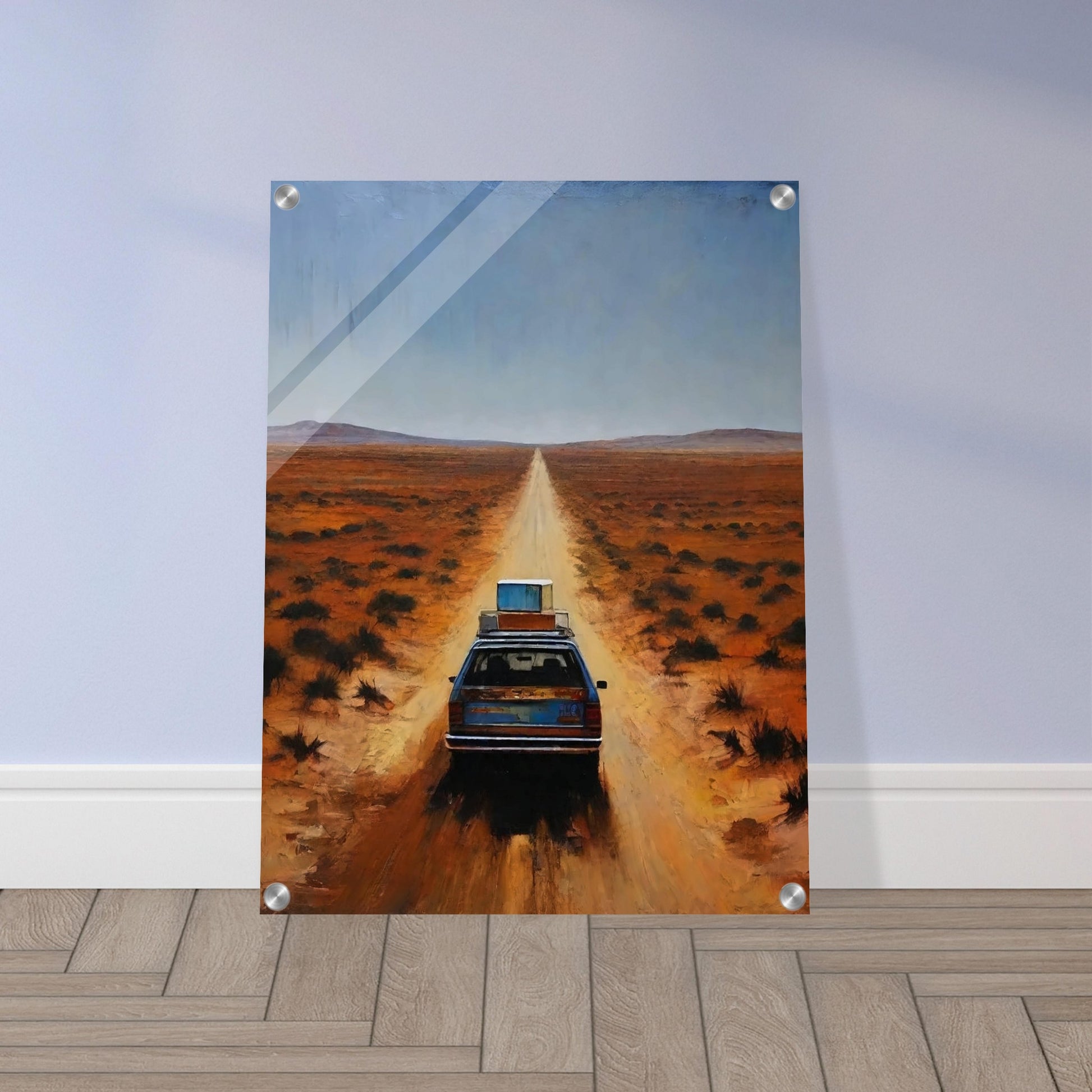 A car driving down a long, desolate road in a vast desert landscape under a clear blue sky.