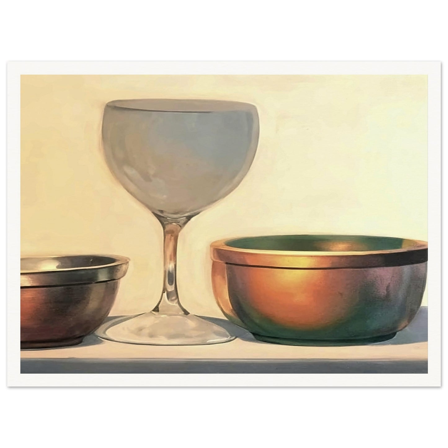 A glass chalice and two metallic bowls arranged in soft light, highlighting their reflective surfaces in a subtle, elegant composition.