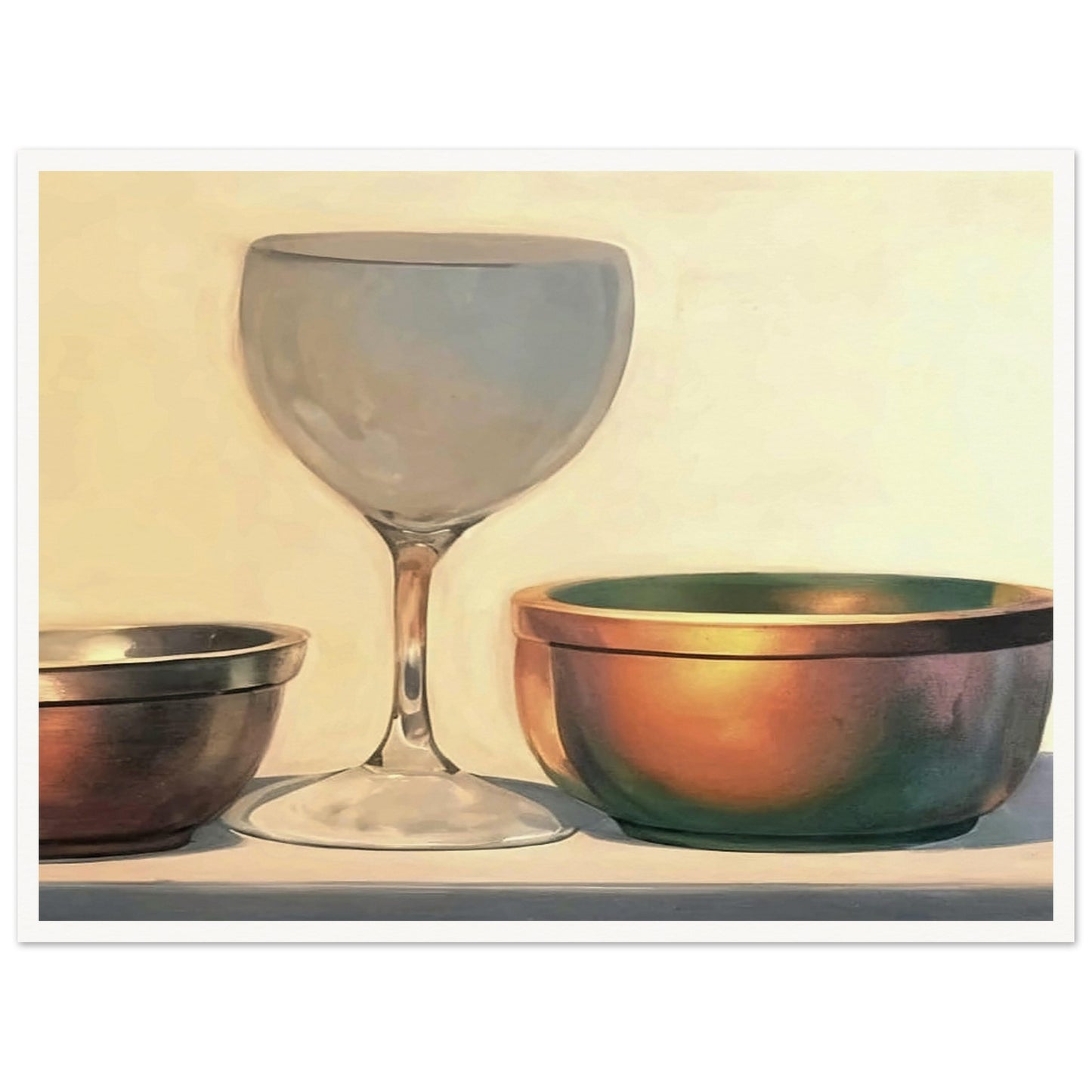 A glass chalice and two metallic bowls arranged in soft light, highlighting their reflective surfaces in a subtle, elegant composition.