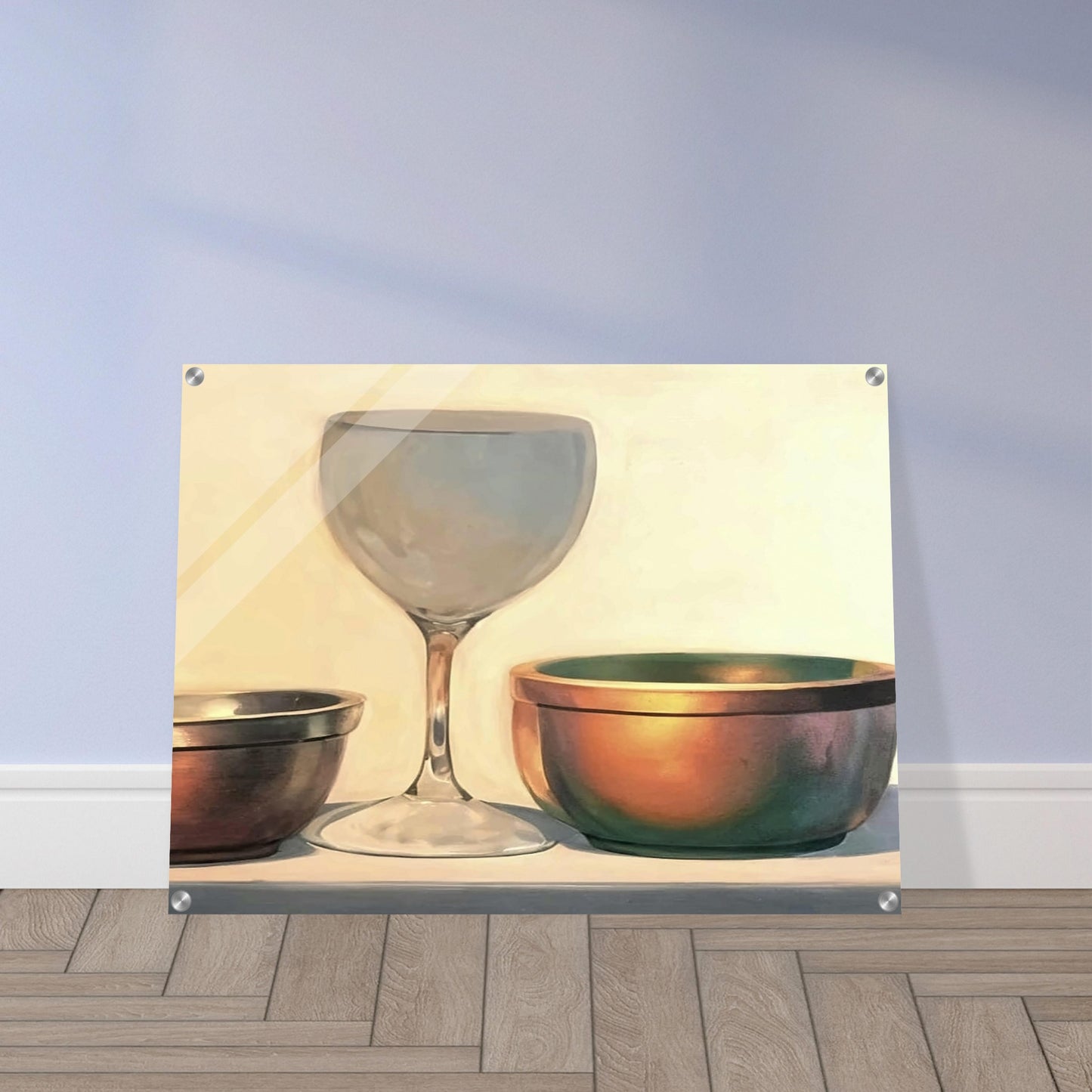 A glass chalice and two metallic bowls arranged in soft light, highlighting their reflective surfaces in a subtle, elegant composition.