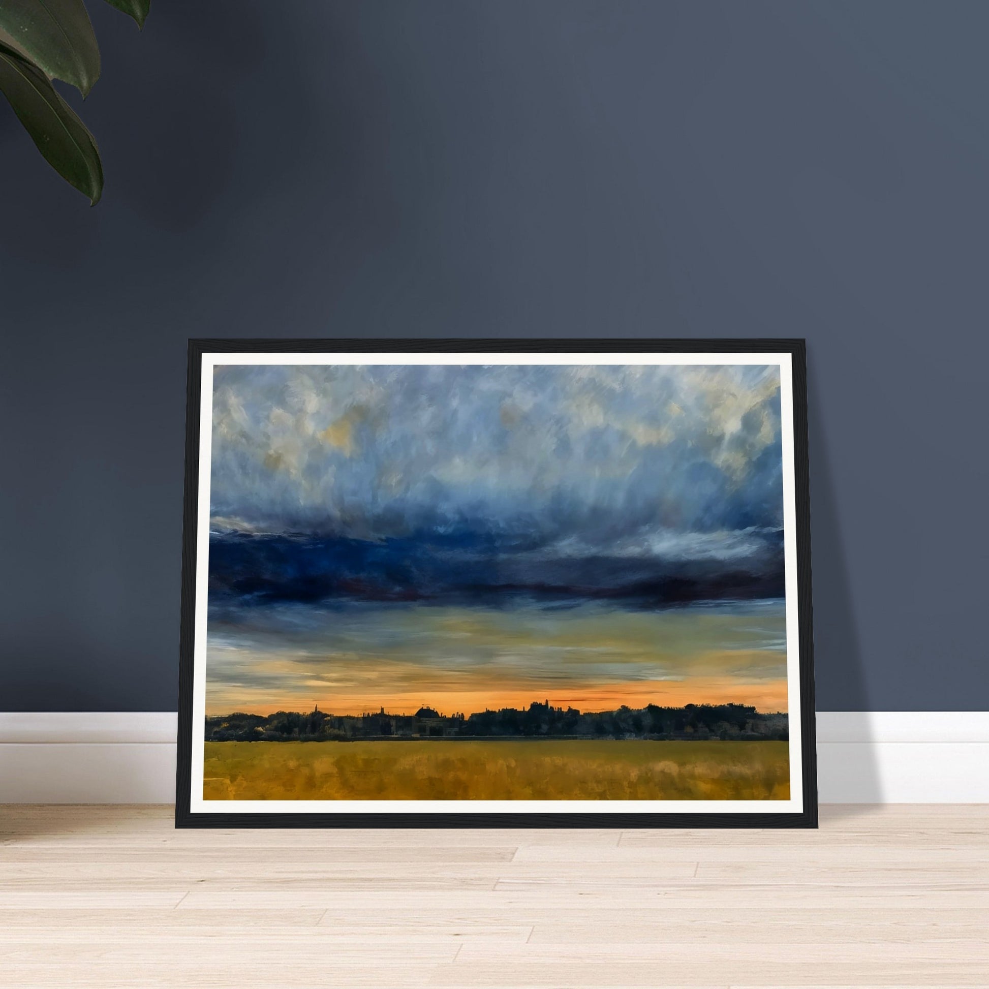 A distant cityscape under a dramatic sky at dusk, with the horizon glowing orange and a vast field in the foreground.