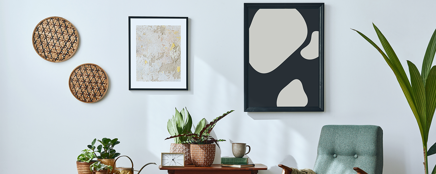 Retro-inspired living room with abstract and textured wall art, wooden furniture, potted plants, and a cozy armchair with a blanket.
