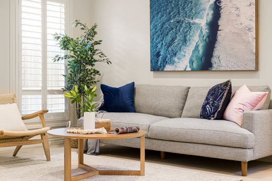 A large beach art print on the wall of a living room setting with neutral colors
