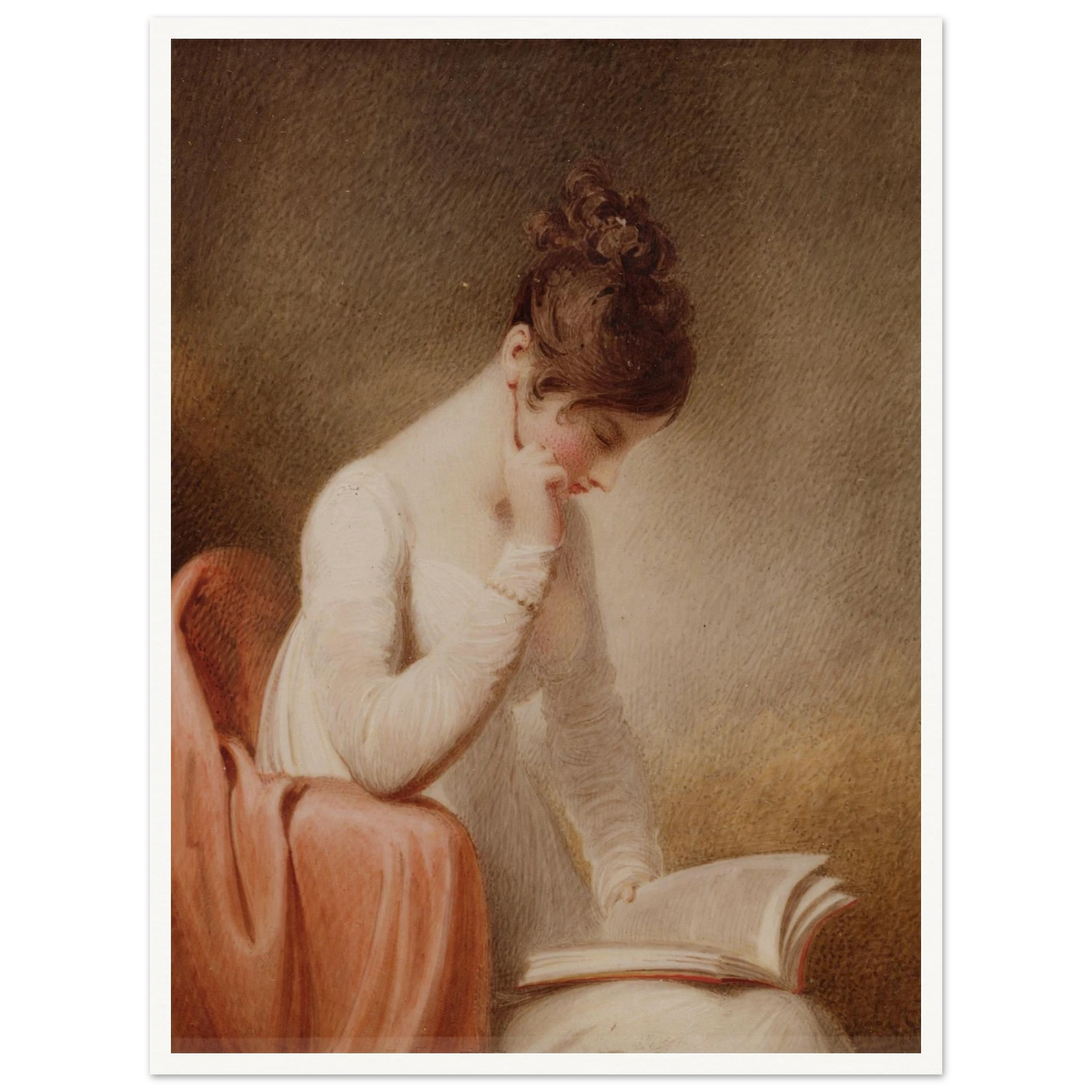 A young woman in a white dress rests her cheek on her hand while reading an open book beside a red chair.
