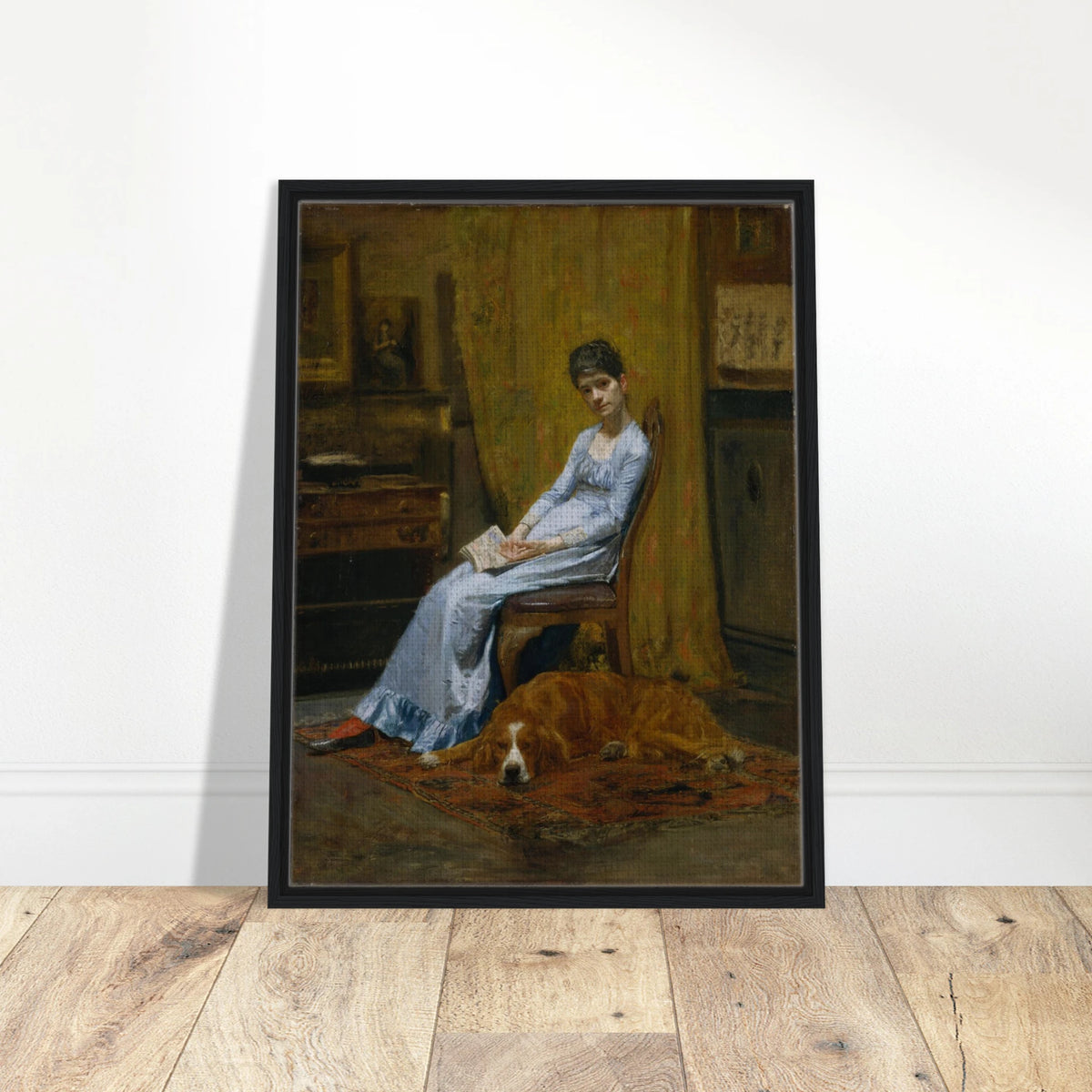 Woman in a blue dress sits with papers beside a sleeping setter dog in a dim studio interior.