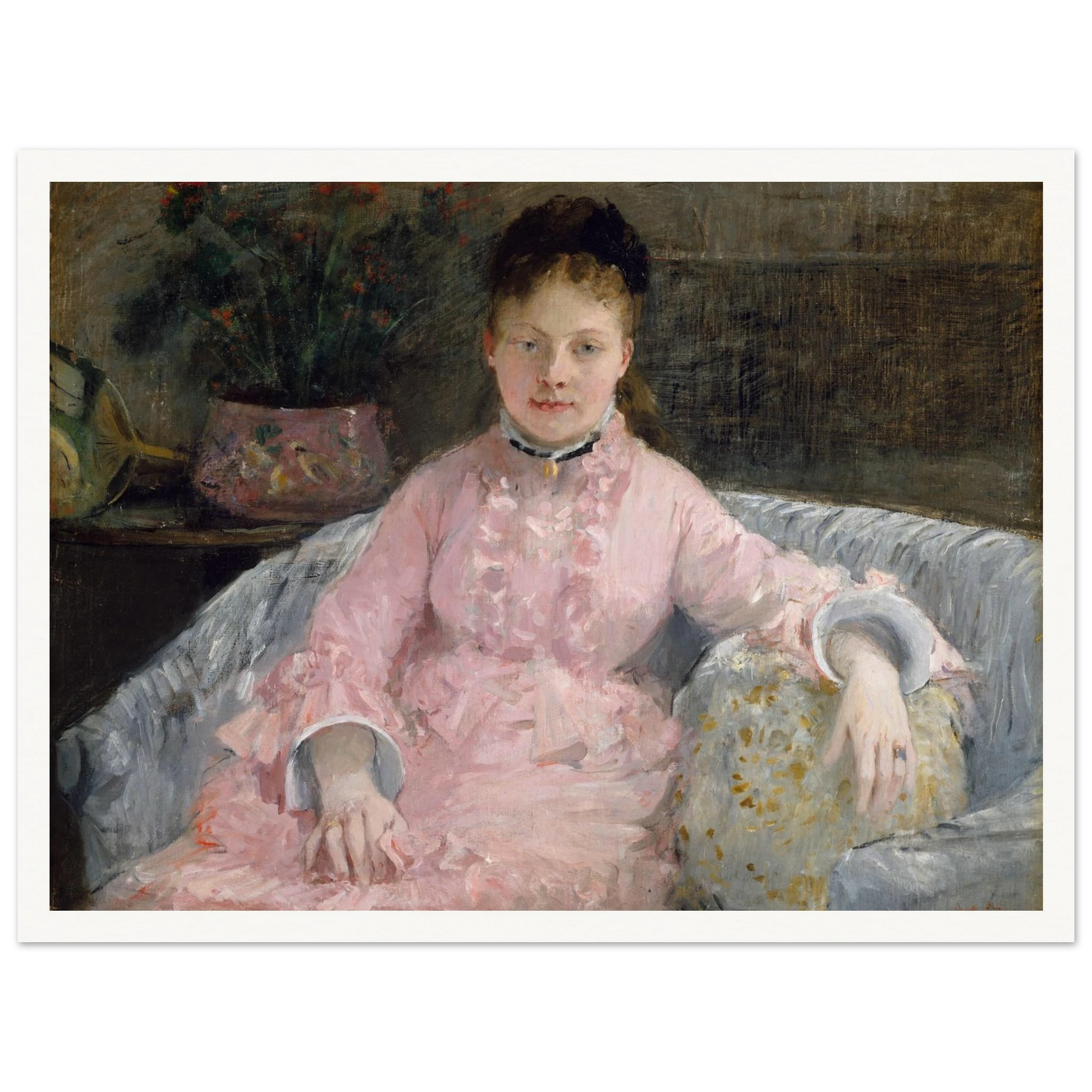 Young woman in a pink dress sits on a sofa beside flowers and a patterned pillow