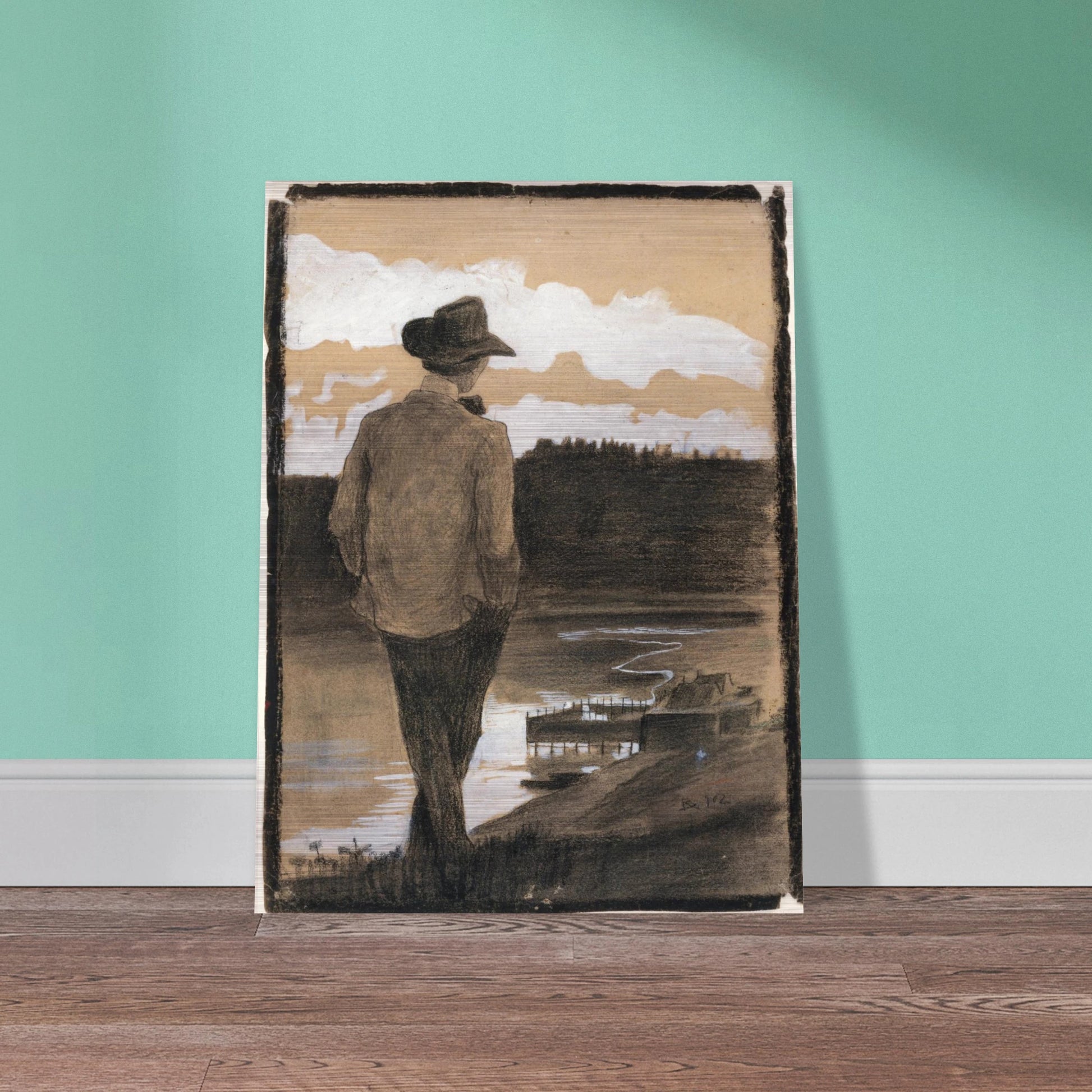 Young man in a hat stands by a riverbank, looking toward clouds and distant water