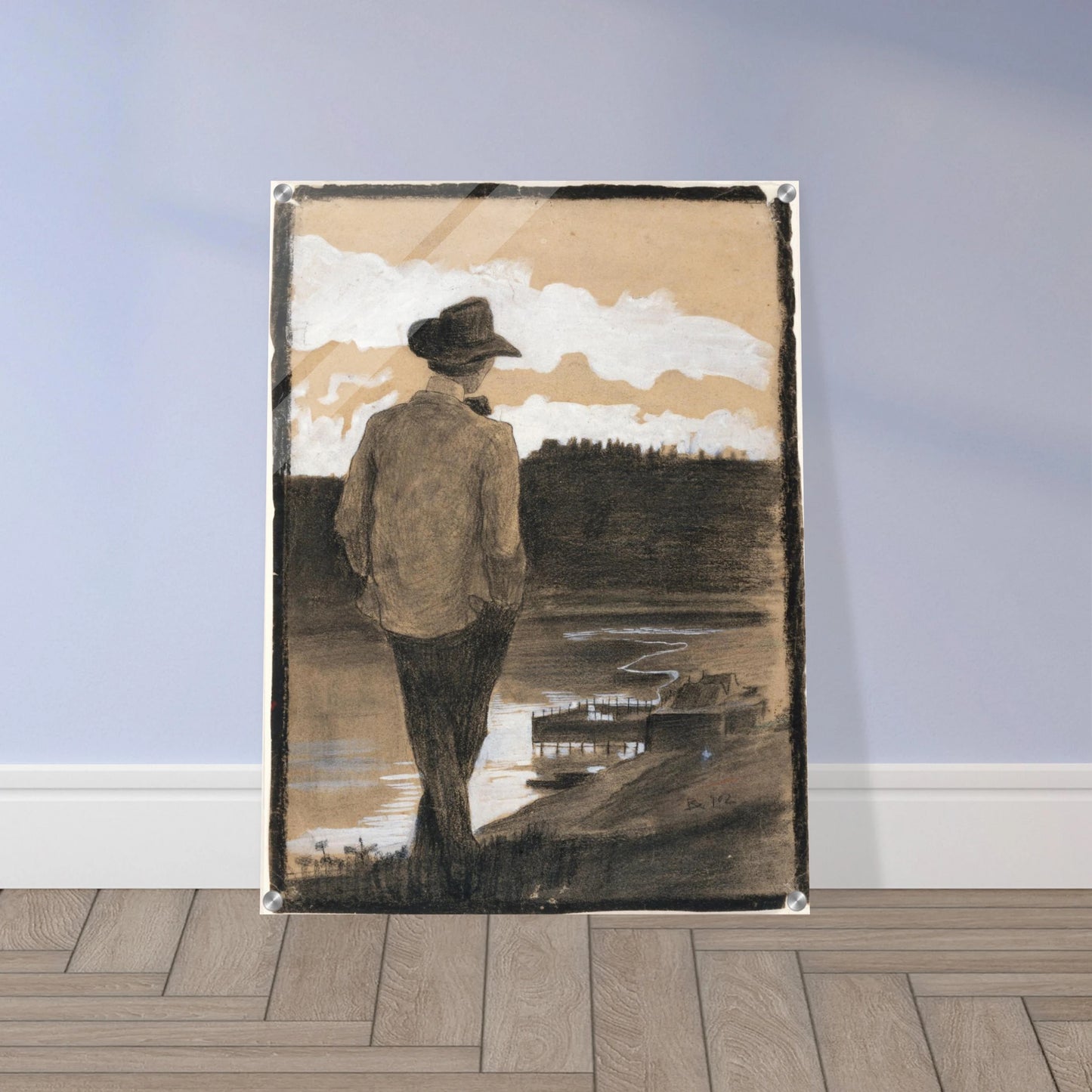 Young man in a hat stands by a riverbank, looking toward clouds and distant water