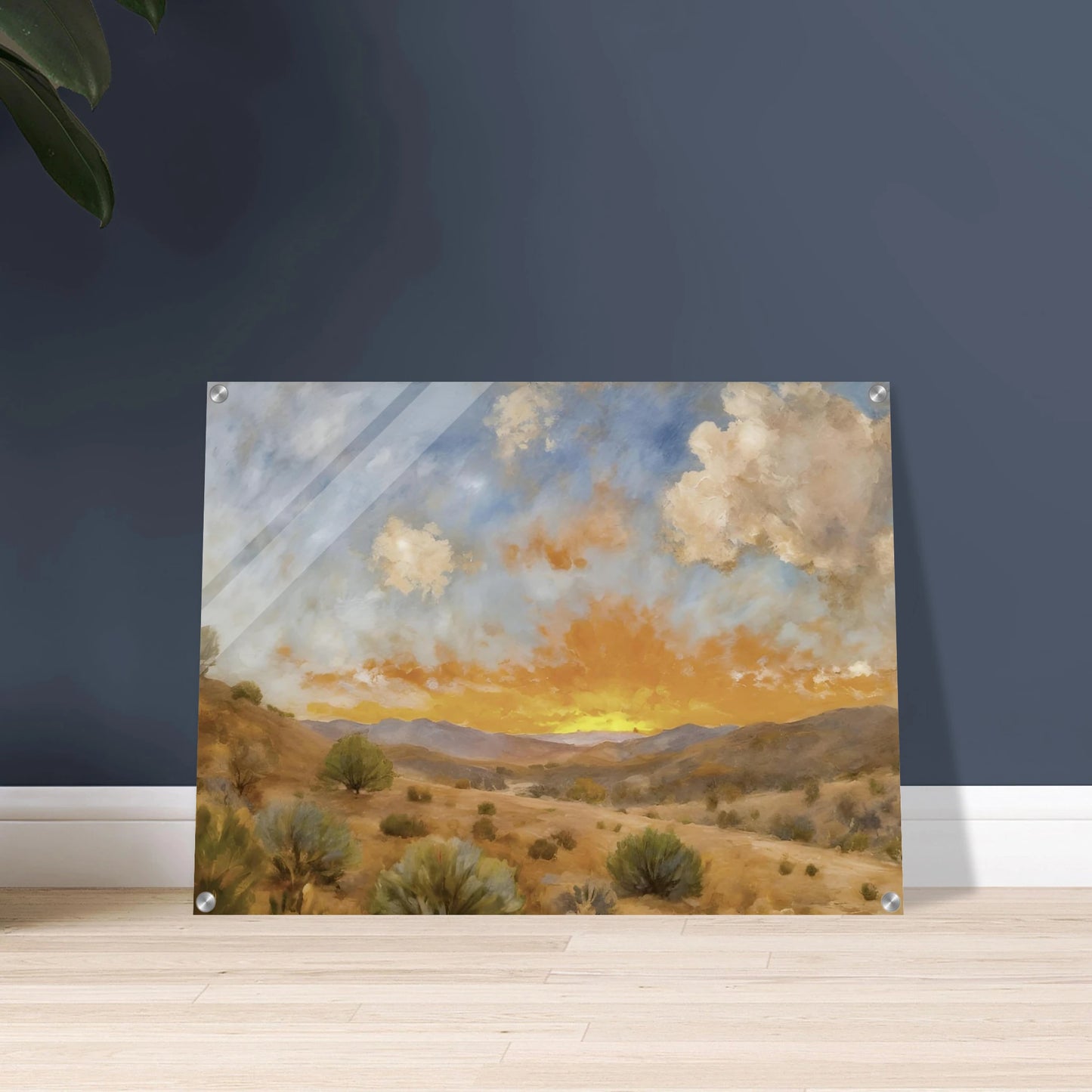 A glowing orange sunset spreads over a tranquil desert valley with scrubby bushes, rolling hills, and dramatic cloud cover.