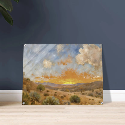 A glowing orange sunset spreads over a tranquil desert valley with scrubby bushes, rolling hills, and dramatic cloud cover.