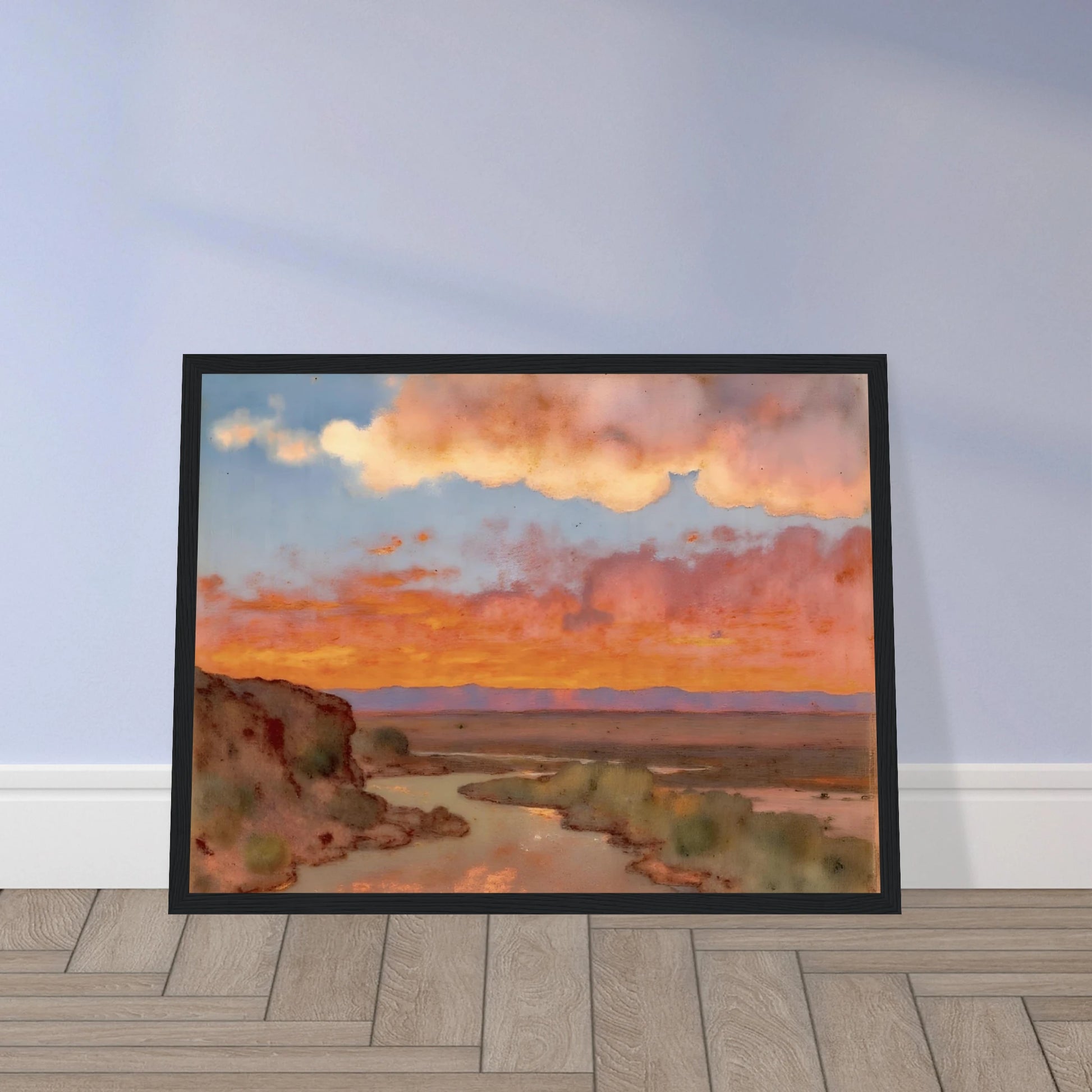 Soft desert river winding beneath glowing orange and pink sunset clouds, with distant plains and muted cliffs in a serene landscape.