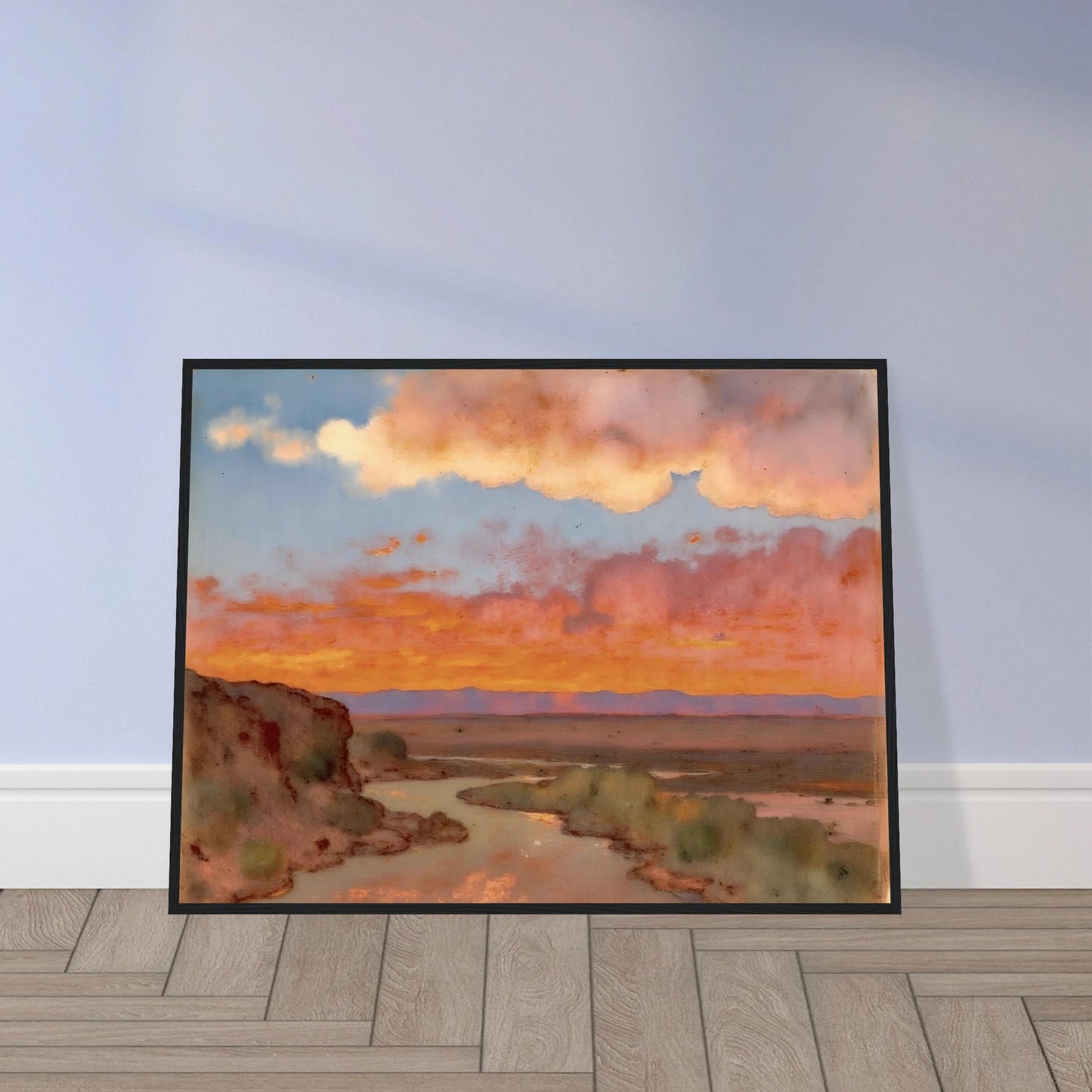 Soft desert river winding beneath glowing orange and pink sunset clouds, with distant plains and muted cliffs in a serene landscape.