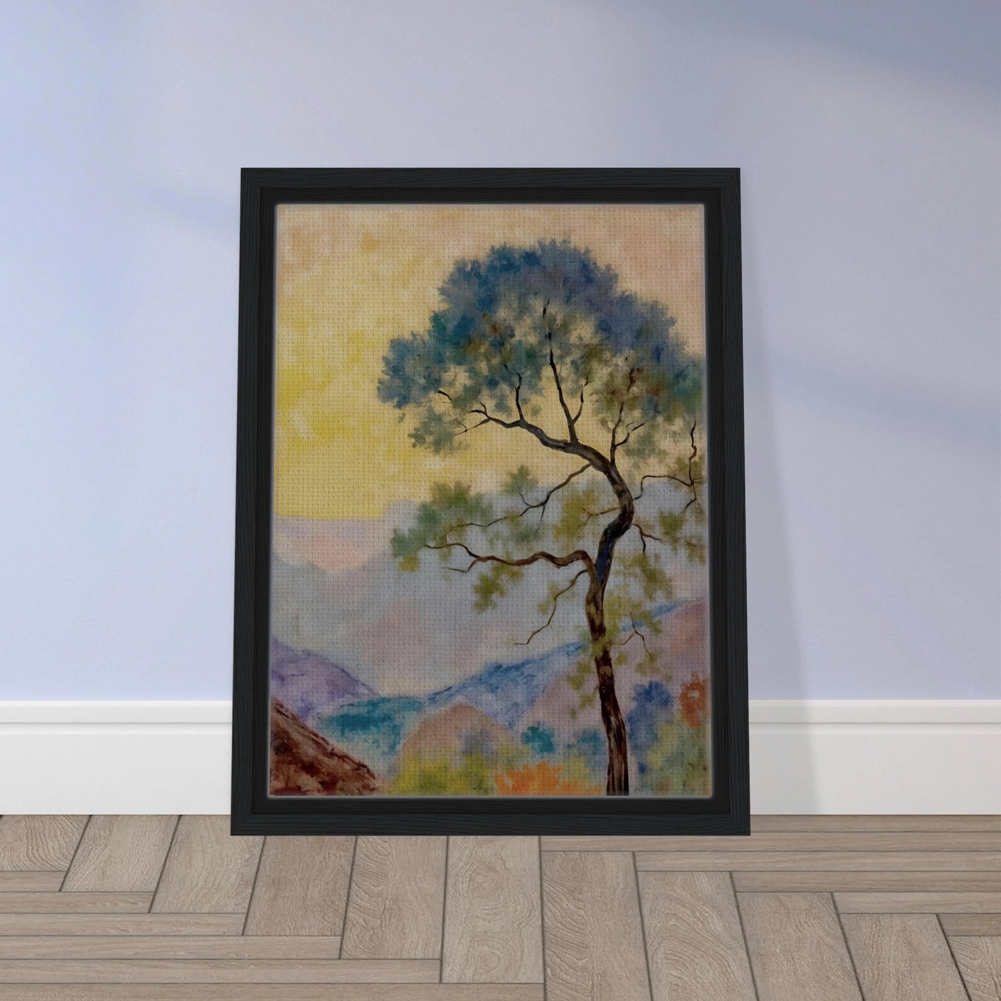 Delicate tree with green-blue foliage standing before pastel mountains under a soft yellow dawn sky.