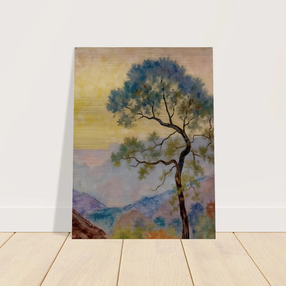 Delicate tree with green-blue foliage standing before pastel mountains under a soft yellow dawn sky.