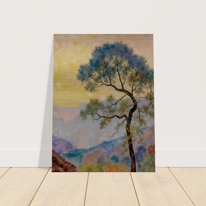 Delicate tree with green-blue foliage standing before pastel mountains under a soft yellow dawn sky.