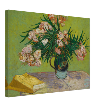 Pink oleanders bloom in a vase beside a yellow book on a green table.