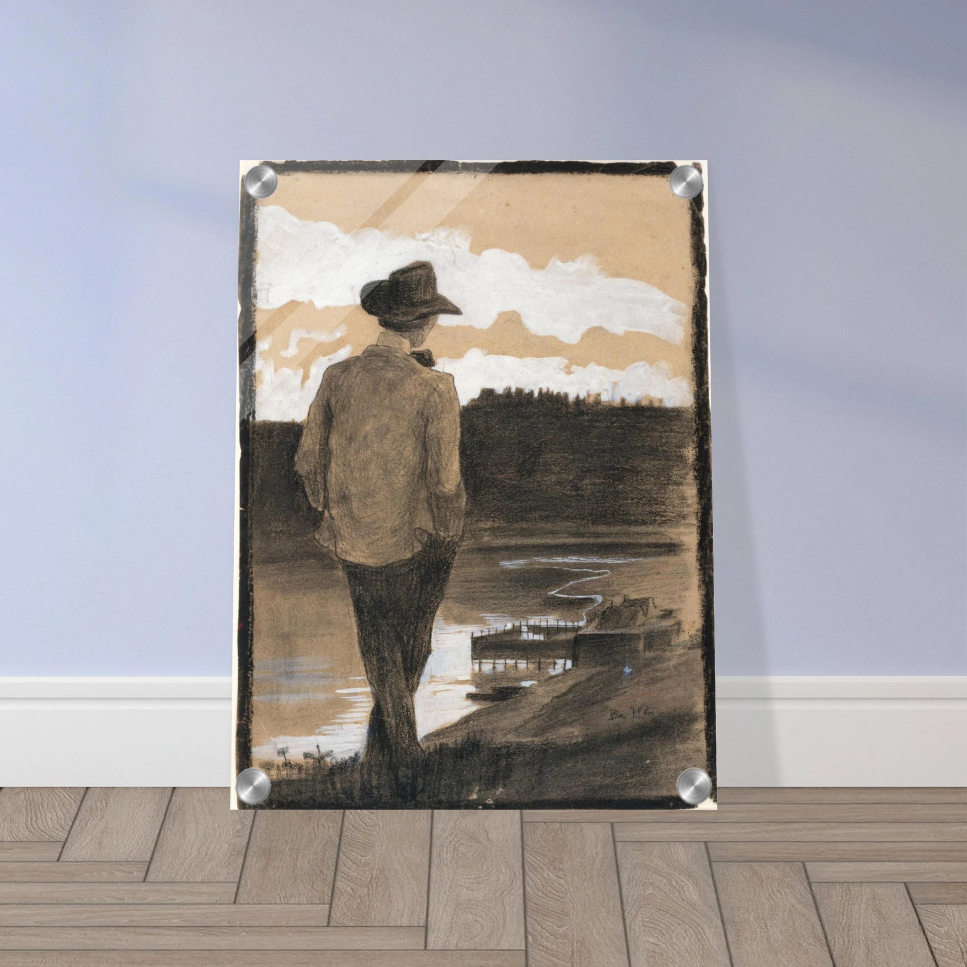 Young man in a hat stands by a riverbank, looking toward clouds and distant water