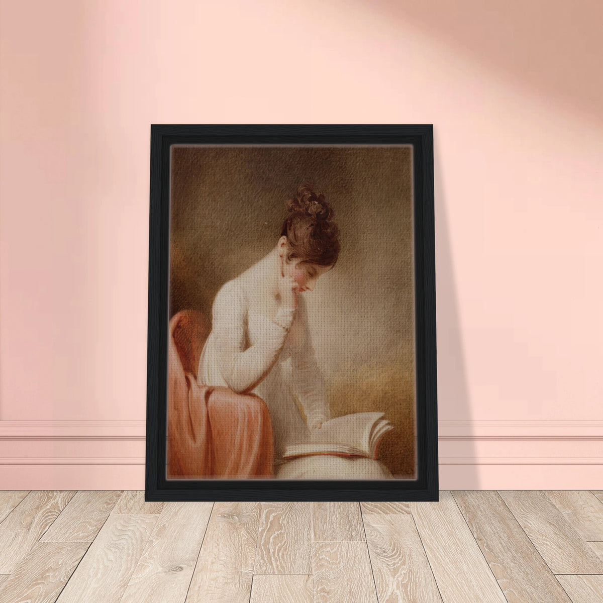 A young woman in a white dress rests her cheek on her hand while reading an open book beside a red chair.
