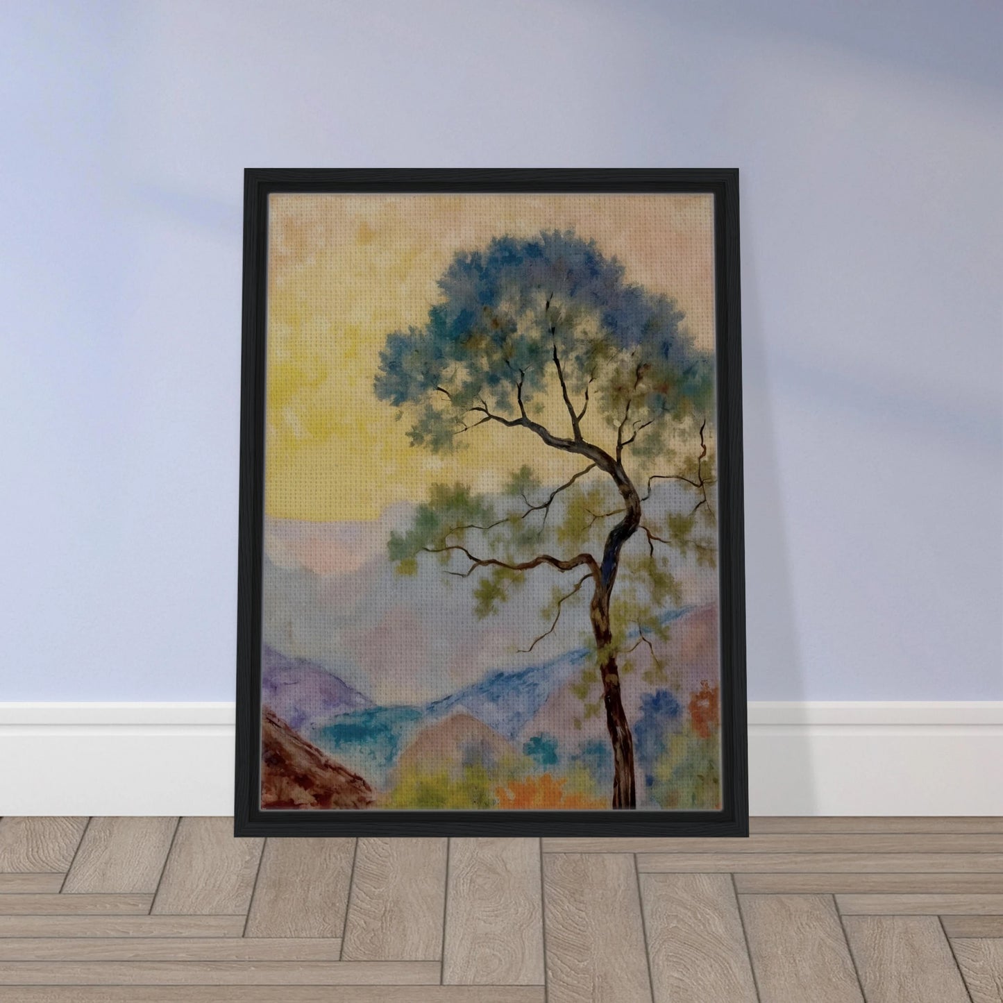 Delicate tree with green-blue foliage standing before pastel mountains under a soft yellow dawn sky.
