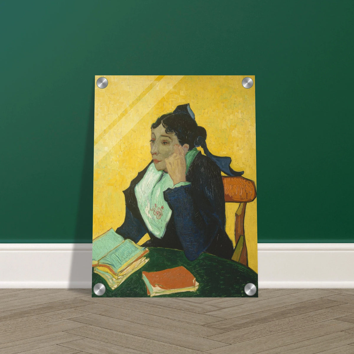Woman in black and green sits at a table with open books against a vivid yellow background.