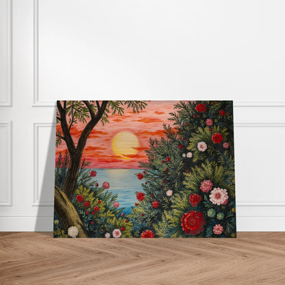 A vivid sunset over the ocean framed by lush bushes filled with red, pink, and white flowers.