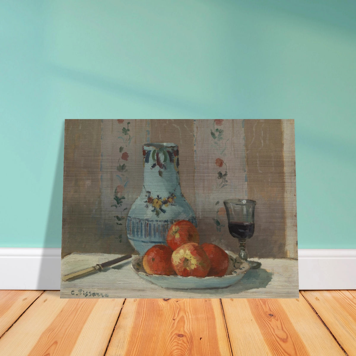 Apples on a plate with a blue pitcher, wine glass, and knife before floral wallpaper.