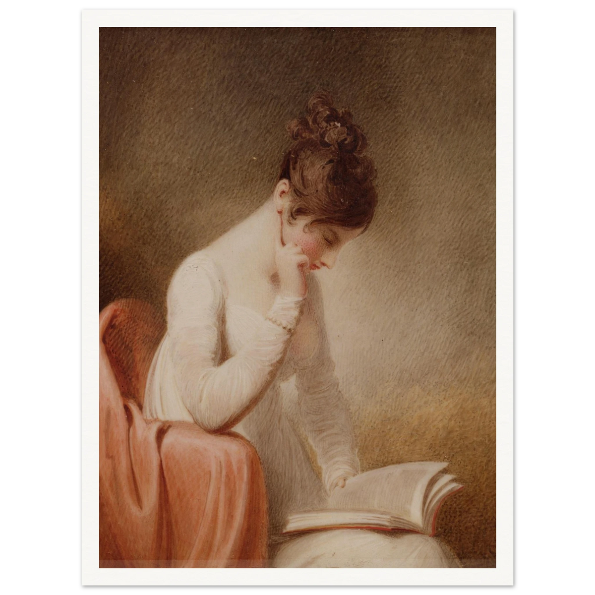 A young woman in a white dress rests her cheek on her hand while reading an open book beside a red chair.