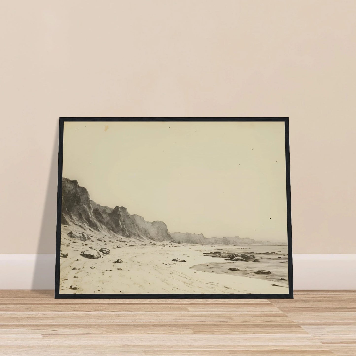 Minimal coastal landscape with pale sandy shore, rugged cliffs, scattered stones, and calm sea rendered in soft monochrome tones.