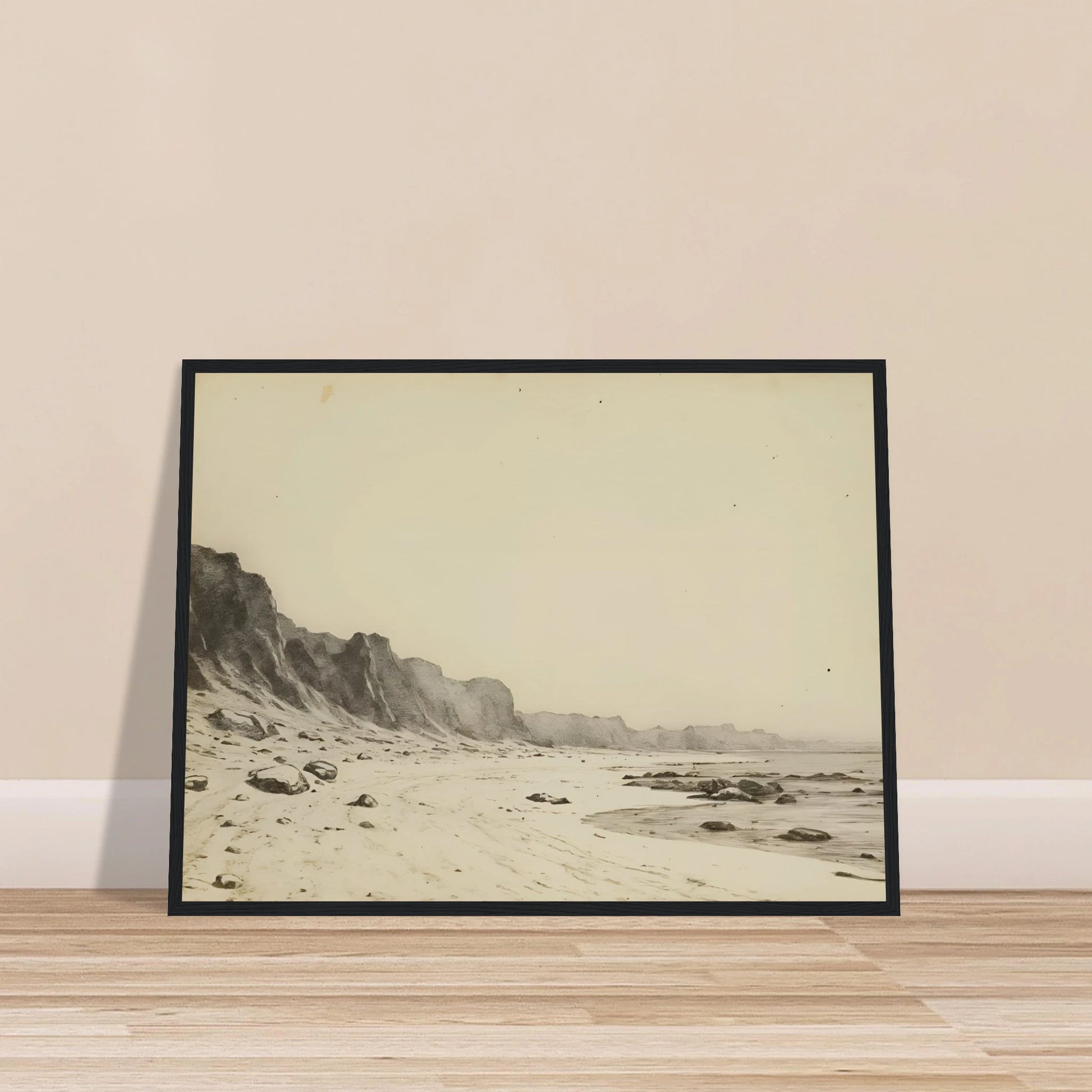Minimal coastal landscape with pale sandy shore, rugged cliffs, scattered stones, and calm sea rendered in soft monochrome tones.