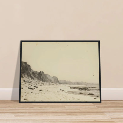 Minimal coastal landscape with pale sandy shore, rugged cliffs, scattered stones, and calm sea rendered in soft monochrome tones.