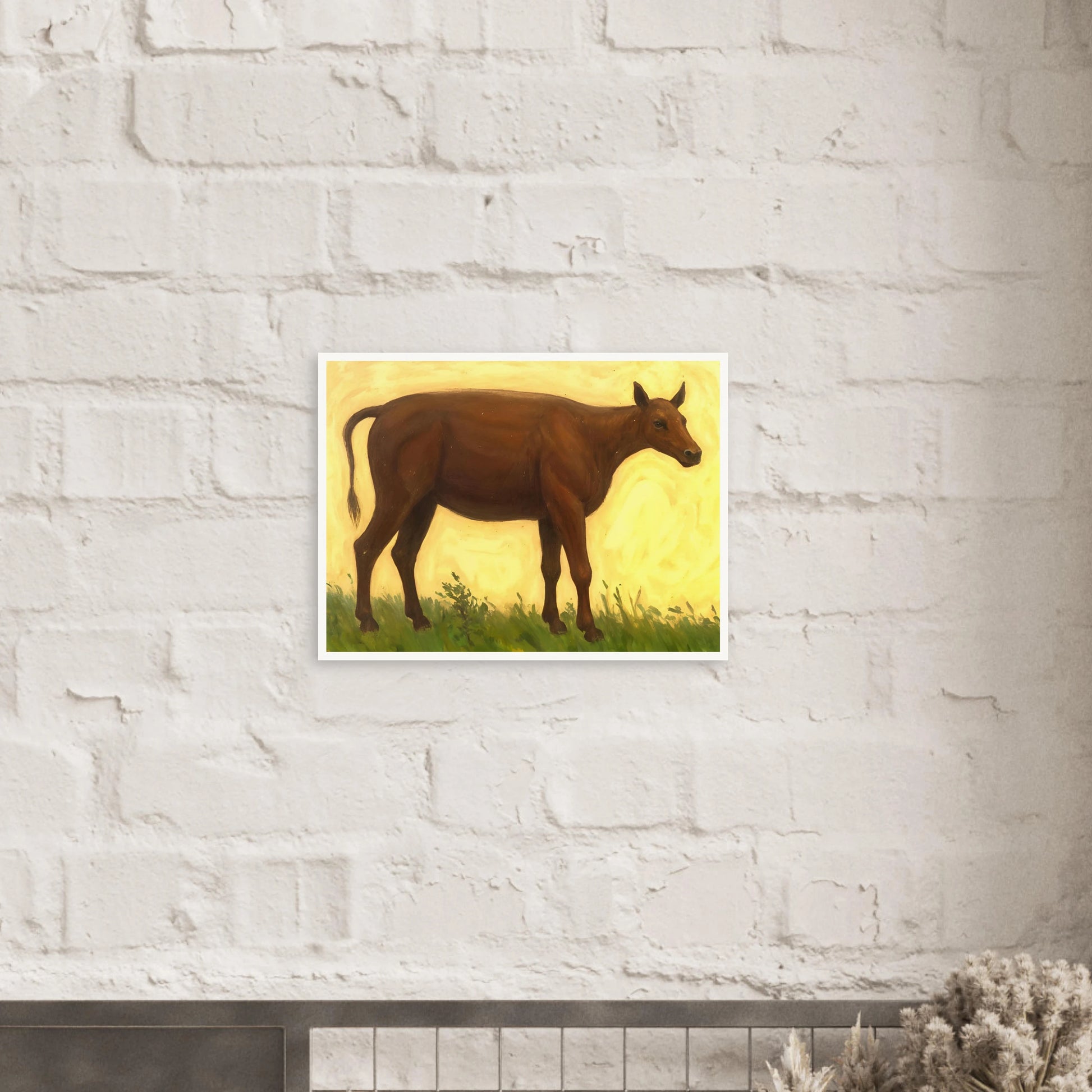 A brown cow standing on grassy pasture against a soft golden-yellow background, exuding calm and simplicity.