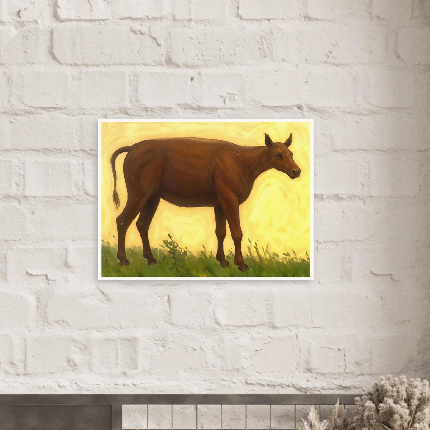 A brown cow standing on grassy pasture against a soft golden-yellow background, exuding calm and simplicity.