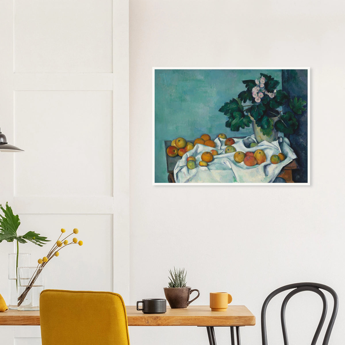 Apples on a white cloth beside a potted primrose plant against a blue-green wall.