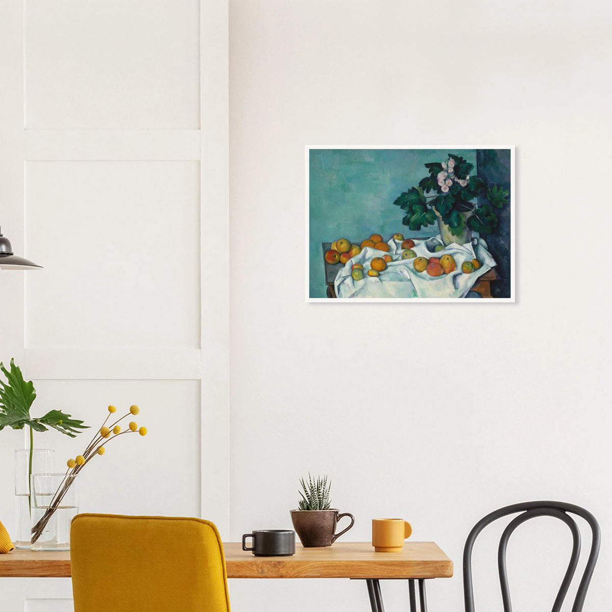 Apples on a white cloth beside a potted primrose plant against a blue-green wall.