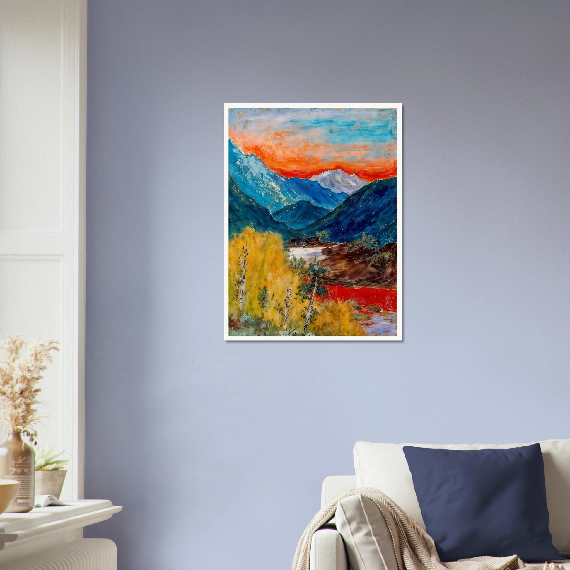 Snow-capped peaks rise above deep blue valleys and golden trees, beneath a fiery sunset glowing across the horizon.