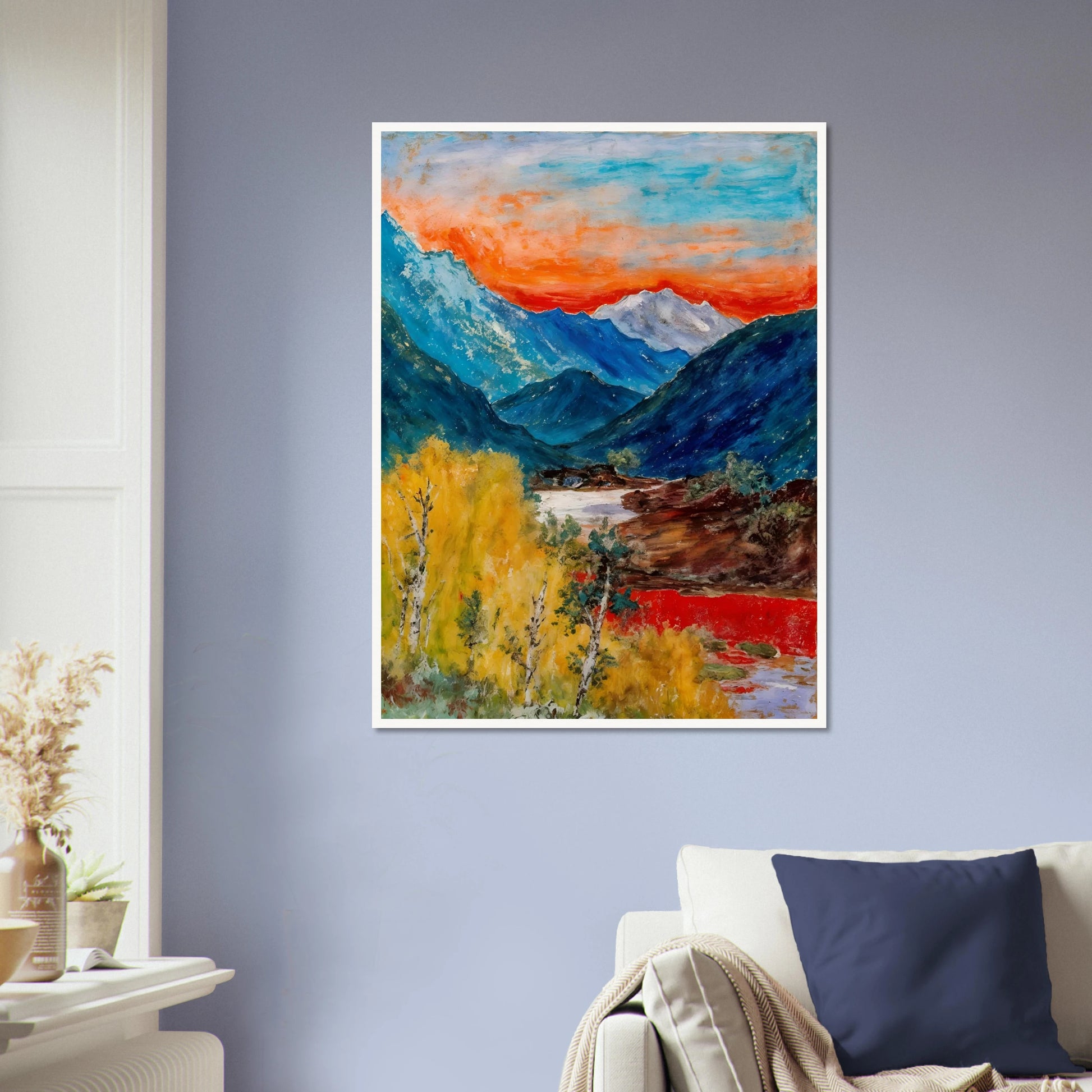 Snow-capped peaks rise above deep blue valleys and golden trees, beneath a fiery sunset glowing across the horizon.