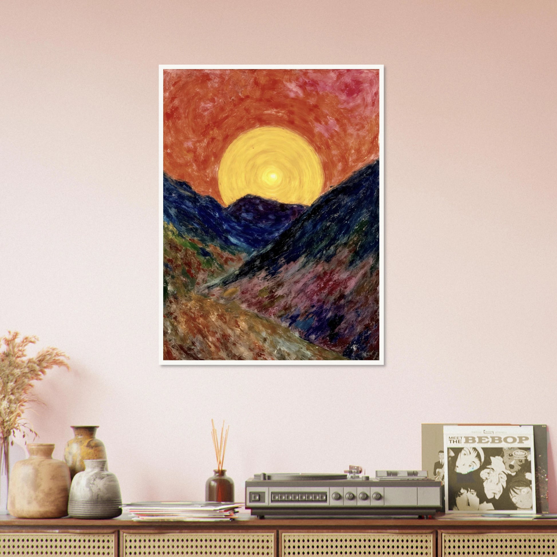 A vivid sunset over deep blue mountains with a glowing golden sun radiating warmth across the textured, colorful valley.
