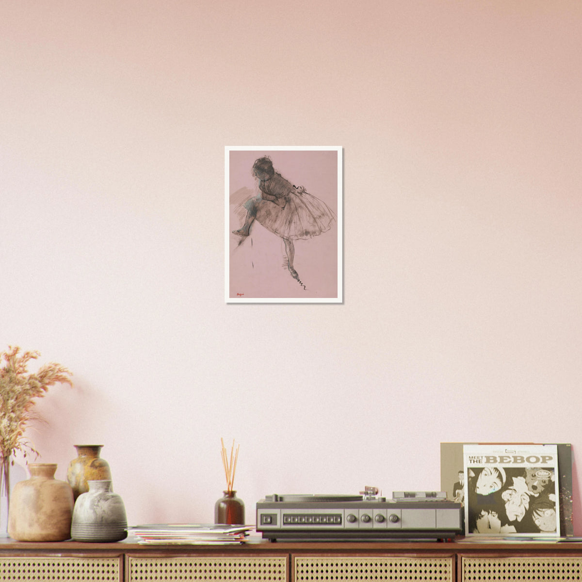 A seated ballerina in a full tutu bends forward, rendered in dark strokes on soft pink paper.