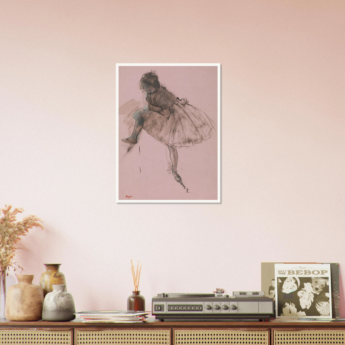 A seated ballerina in a full tutu bends forward, rendered in dark strokes on soft pink paper.