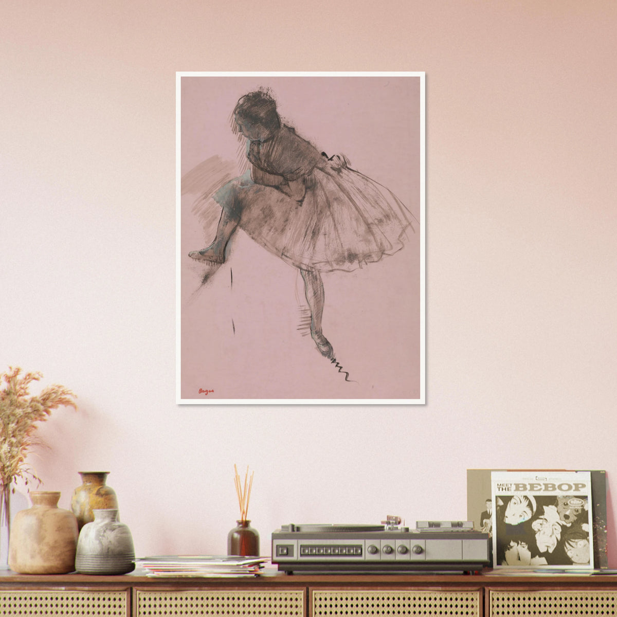 A seated ballerina in a full tutu bends forward, rendered in dark strokes on soft pink paper.