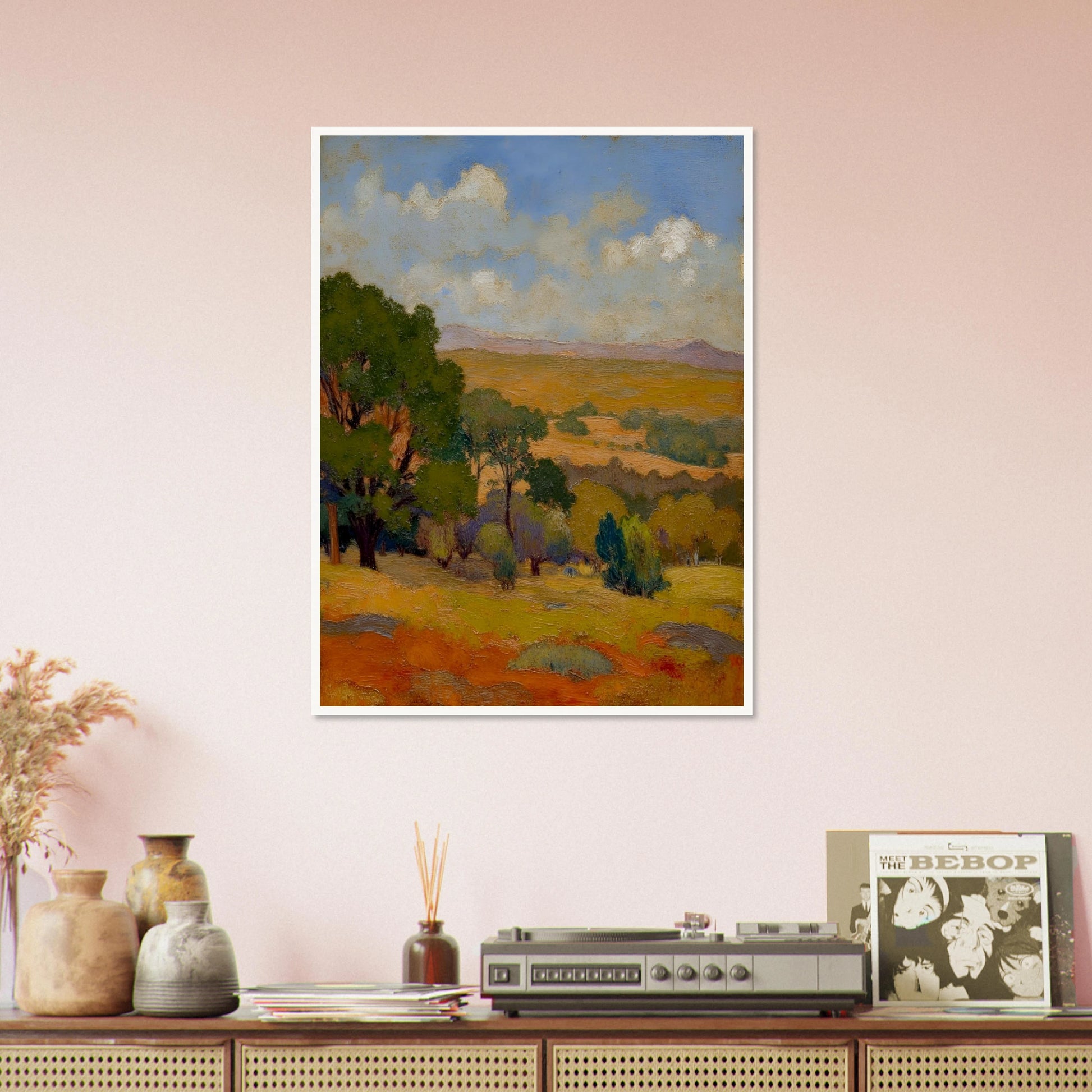 Golden fields and green trees stretch beneath a blue sky with soft clouds and distant hills.
