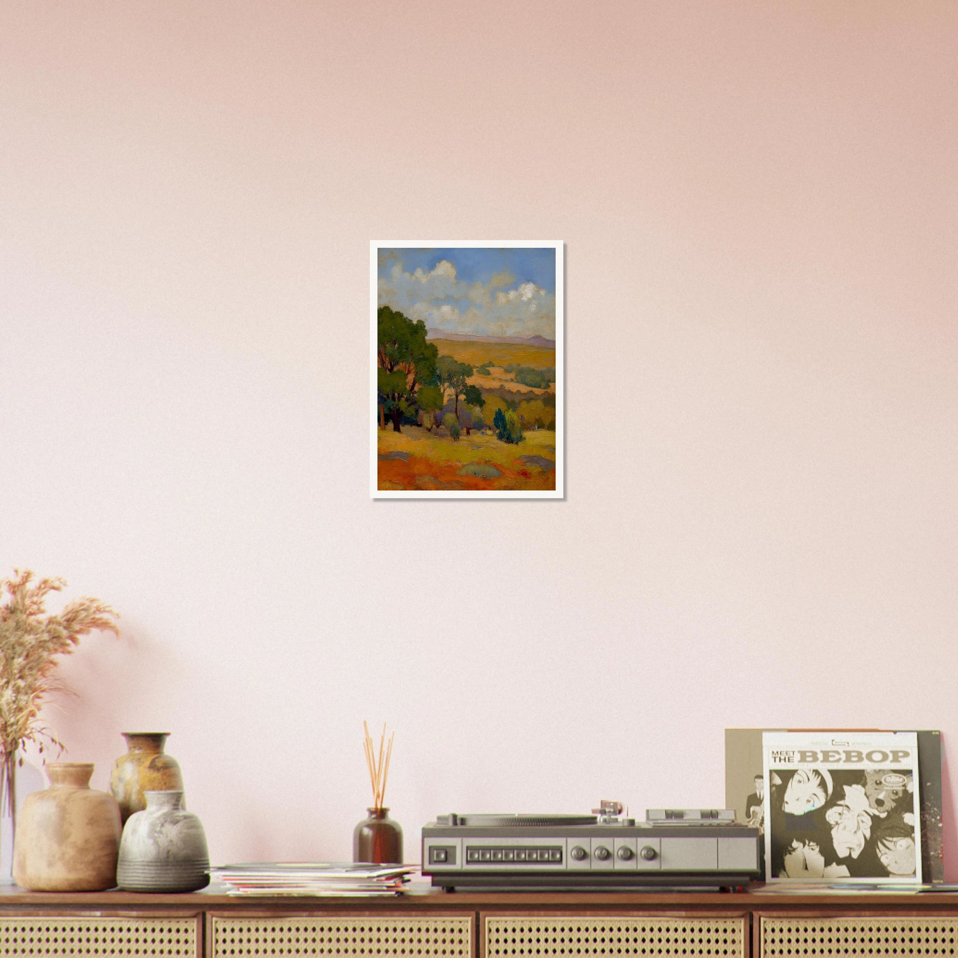 Golden fields and green trees stretch beneath a blue sky with soft clouds and distant hills.