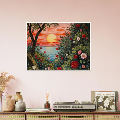 A vivid sunset over the ocean framed by lush bushes filled with red, pink, and white flowers.