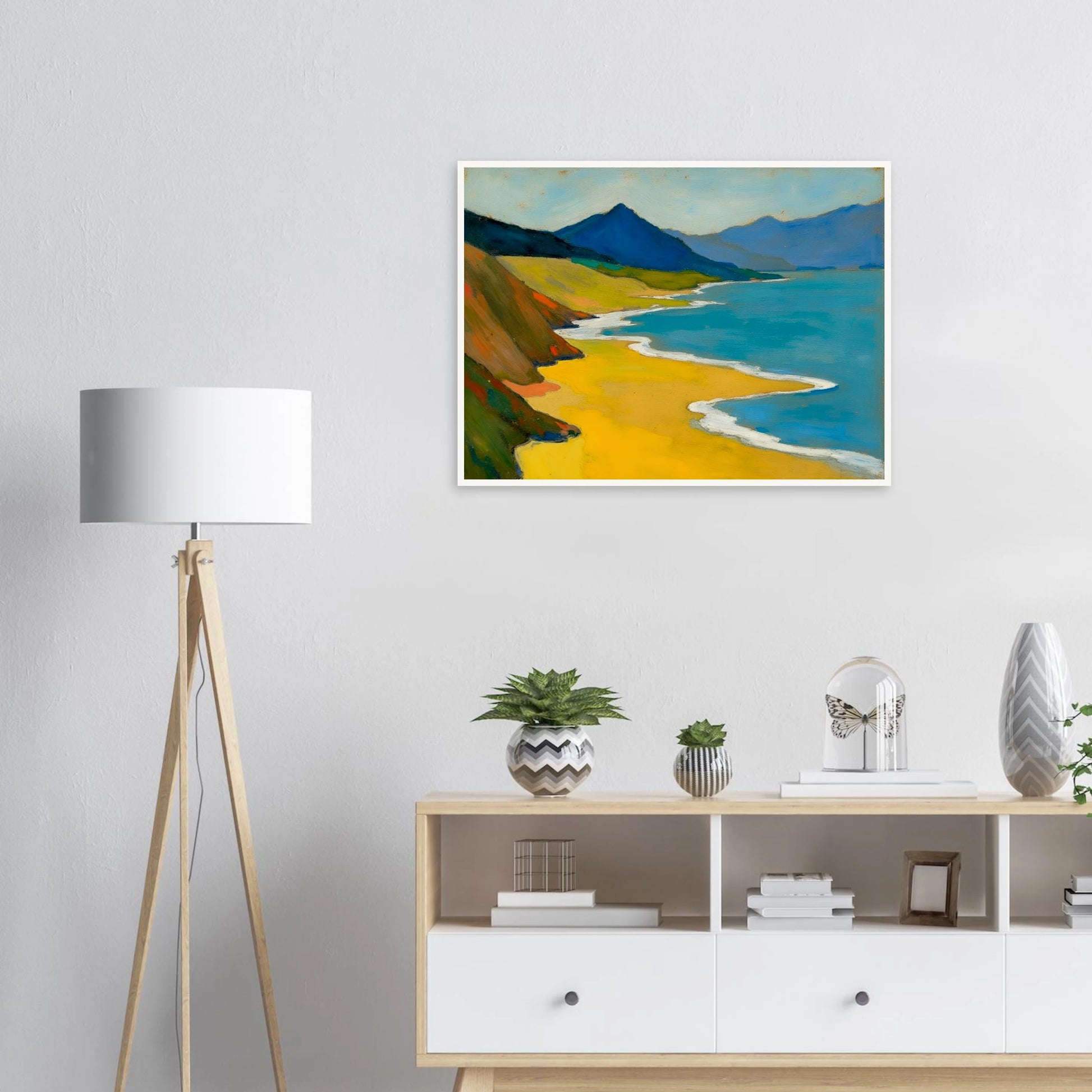 Golden shoreline curves beside turquoise water, green hills, and blue mountains under a pale sky.