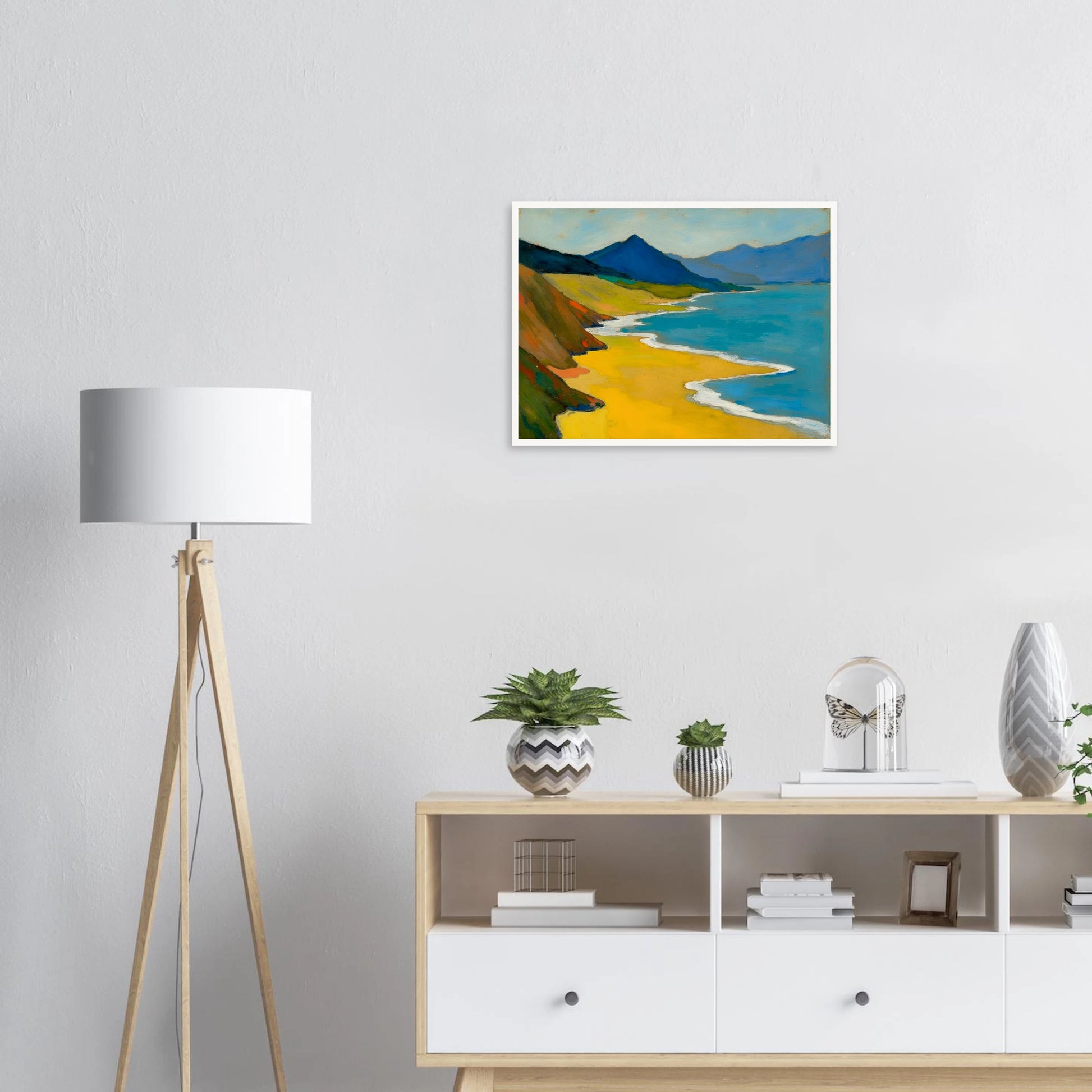 Golden shoreline curves beside turquoise water, green hills, and blue mountains under a pale sky.