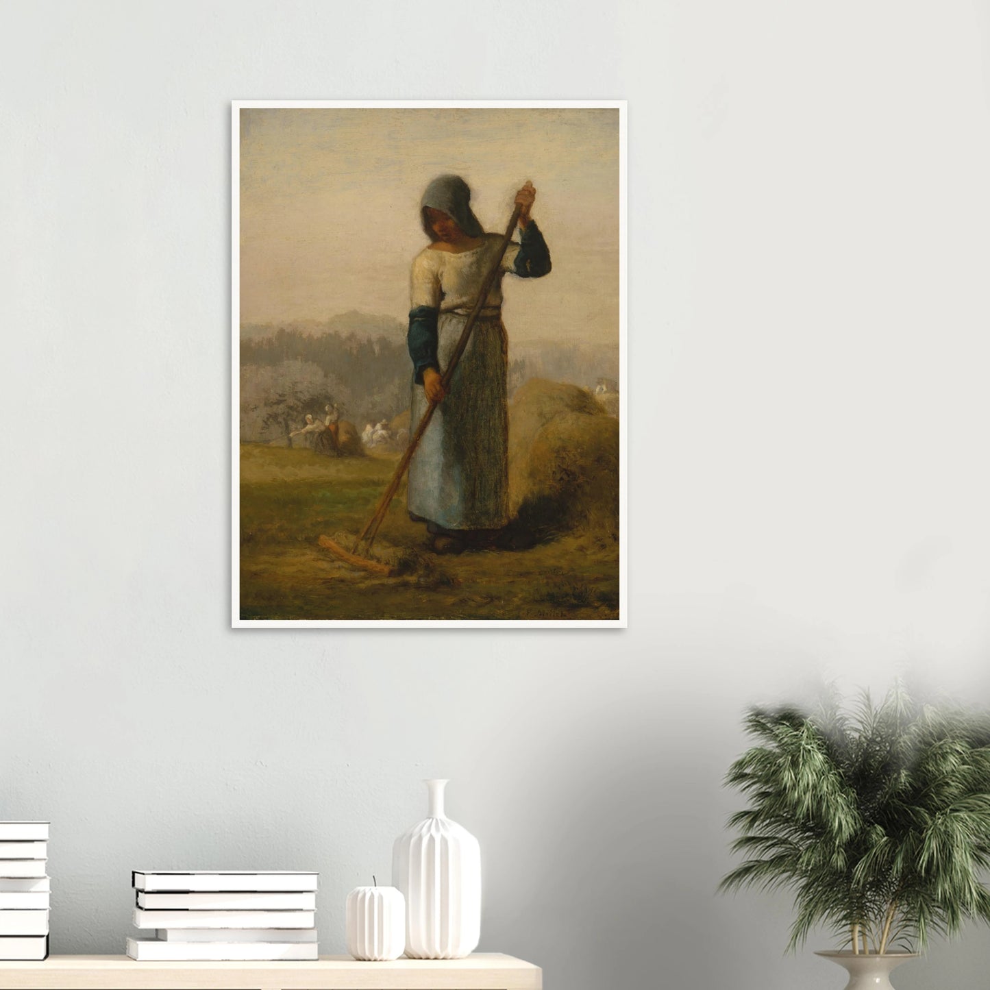 A peasant woman holds a wooden rake beside a haystack as farm workers gather hay in a distant field.